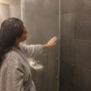 Homeowner checking condensation levels on shower screen after hot shower